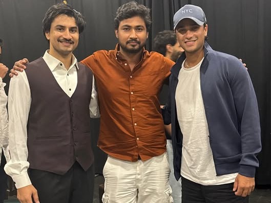 Three actors backstage in front of black curtains