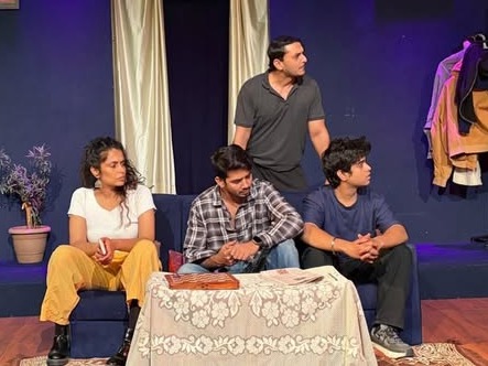 Four actors in a living room scene on stage
